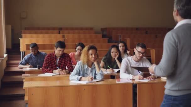 Πολυεθνική ομάδα φοιτητών απαντώντας σε ερωτήσεις καθηγητές, έξυπνη νέοι άνθρωποι μιλούν και χαμογελώντας ενώ δάσκαλος ζητά από τους έλεγχος γνώσεων. — Αρχείο Βίντεο