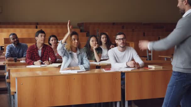 Wielorasowe studentów są podnoszenie rąk i odpowiedzi na pytania nauczycieli, facet w okularach daje poprawne odpowiedzi i chluby o tym. Koledzy i koncepcja. — Wideo stockowe