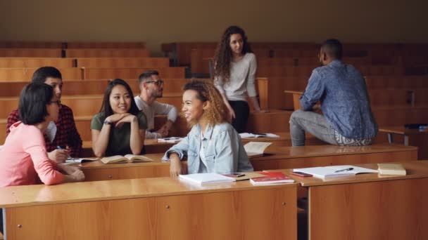 Mnohonárodnostní skupiny studentů se uvolnil a chatování během přestávky si užívat volného času a komunikaci. Dřevěné stoly, atraktivní lidé a noteboks jsou viditelné. — Stock video
