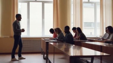 Sakallı adam üniversite öğretmen yetişkin öğrenciler için ders okuma ve el hareketi, gençlerin yazma ve onu dinlemeyi. Yüksek eğitim ve gençlik kavramı.