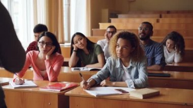 Yorgun ve bıkkın öğrenciler öğretmen için dinleme ve notlar Notebook masaları Üniversitesi'nde oturan yapma. Eğitim, can sıkıntısı, gençler ve sınıf kavramı.