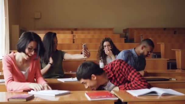 Zorgeloos studenten plezier na lezing gooien van papier, tekening in laptops, vechten en lachen. Ondeugende concept van jeugd, onderwijs en ontspanning. — Stockvideo