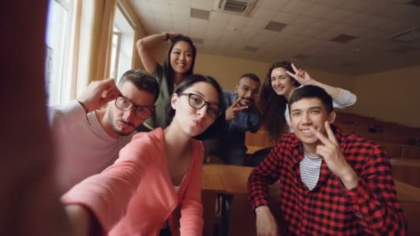 面白い魅力的な若い男性と女性の Selfie を講堂 教科書でポーズと手のジェスチャーと表情を示すの視点ショット — ストック動画