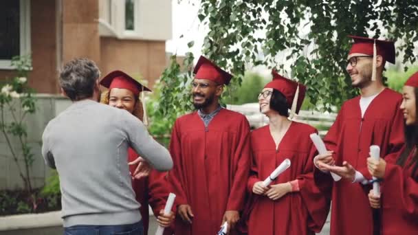 Vänliga stolt professor kramar glad African American girl student och skakar hennes hand sedan önskar lycka till mulninational grupp av studenter. — Stockvideo