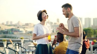 Erkek ve kadın açık hava partisinde sohbet sonra sarılma, el sallayarak ve onu öpmek, şişe tungur ve alkol içme onların arkadaş hipster tebrik.
