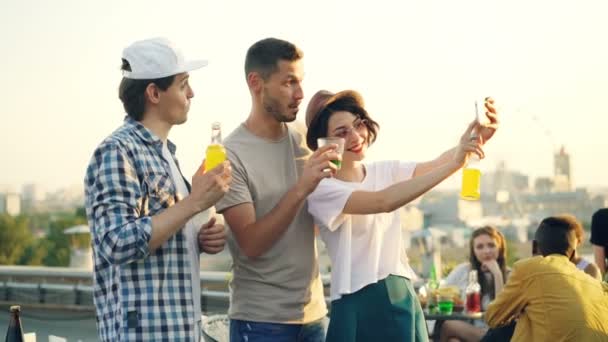 Hezká mladá žena používá smartphone aby selfie s kamarády veselý muž, mladí lidé představují pak se smíchem a pozoroval vtipné fotky. — Stock video