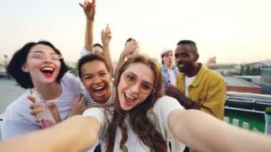 Bakış açısı Genç Bayan blogger yazmak video dans ve arkadaşları ile eğlenmek çatı partisi onun blog için bir kadeh. Vlogging, gençlik ve disko kavramı.