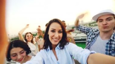 Bakış açısı shot kamera tutarak ve dans, gülen ve kameraya bakarak mutlu insanlar ile çatı partisi kayıt genç kadın. Gençlik ve eğlence kavramı.