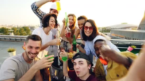 Ponto de vista de jovens homens e mulheres tomando selfie com garrafas, desfrutando de refrigerantes, bebendo e posando com rostos engraçados. Estilo de vida moderno e conceito de bebida . — Vídeo de Stock