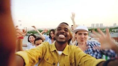 Afrikalı Amerikalı erkek video blogcusu çatıdaki arkadaşlarıyla parti hakkında video kaydediyor. İnsanlar kameraya bakıyor, dans ediyor ve konuşuyor..