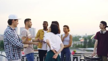 DJ yakışıklı olan kulaklık özel ekipman ile karıştırma süre çekici genç insanlar üzerinde çatı zevk müzik dans ediyorlar. Parti, şehir ve gençlik kavramı.