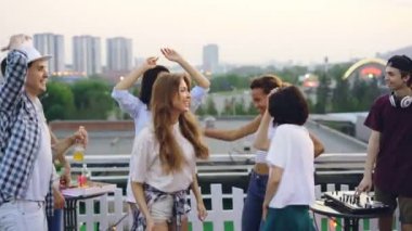 Genç erkek ve kadınların müzik ve Dj ile karıştırma konsol çalışıyor erkek sırasında eğlenmek çatı üzerinde dans ediyor. Parti, sevinç ve modern yaşam kavramı.