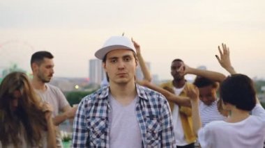 Üzgün yüz ile ayakta dışında sonra mutlu bir şekilde arkadaşlarıyla dans yakışıklı genç hipster ani ruh hali salıncak. Duygusal değişim, parti ve insanlar kavramı.