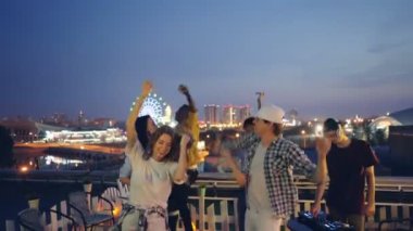 Arkadaşlar çok ırklı grup çatıda açık partide Dj Ekipmanları ile çalışma ile dans ediyor. Modern şehir gece hayatı, gençlik ve eğlence kavramı.