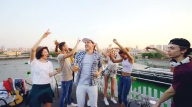 Yavaş dans ve soğuyunca gülüyor kadın ve genç erkek Dj karıştırma konsolu ile yaz gününde çatı partide çalışıyor. Eğlence, gençlik ve müzik konsepti.