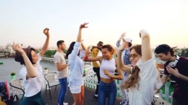 Yavaş hareket ederken onların arkadaşı Dj kulaklık giyen ekipman ile çalışan müzik karıştırma eğleniyor çatı üzerinde dans gençlik. Parti, kutlama ve eğlence kavramı.