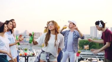 Açık hava partisinde dijital mikser ile çalışan profesyonel Dj dans çekici kızlar ve çocuklar öğrenci ağır çekim. Arkadaşlar şişe tutan ve having fun.