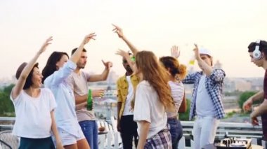 Yavaş dans arkadaşlar müzik ritim zevk ve DJ karıştırma konsol ile çalışıyorken gülerek el kaldırdı. Çatı partisi, modern yaşam tarzı ve gençlik kavramı.