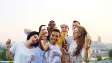 Ağır çekim oldukça Afrikalı-Amerikalı kadın arkadaşlarıyla dans ve smartphone kameraya bakarak çatı partisi video kaydı. Eğlence, gençlik ve müzik konsepti.