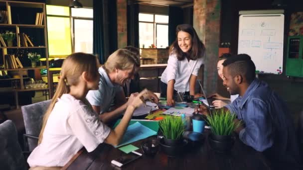 Groupe multi-ethnique de personnes discute du projet, puis fait haute-cinq assis au bureau dans la salle de bureau. Mes collègues rient et parlent amicalement. .