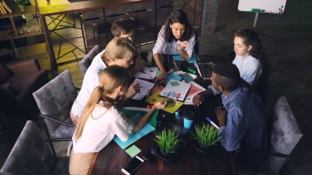 Multiracial team is analyzing charts and graphs during business meeting then clapping hands and doing high-five expressing support, unity and successful work. — Stock Video