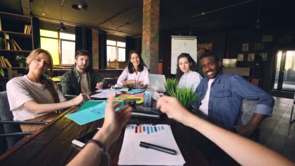 Les employés de bureau sourient et rient en regardant la caméra pendant la séance d'information avec le PDG assis au bureau pendant la journée de travail. Ambiance conviviale et concept de travail d'équipe . — Video