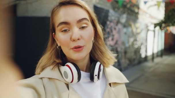 Punto de vista de la toma de la mujer tienen chat de vídeo en línea hablando y haciendo gestos de pie al aire libre en la ciudad moderna. Redes sociales, personas y concepto de tecnología . — Vídeo de stock