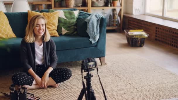 Chica guapa maquillaje artista y blogger está grabando vídeo sobre el nuevo producto cosmético utilizando la cámara, ella está sosteniendo kit de maquillaje, hablando y tocándolo con el dedo . — Vídeo de stock