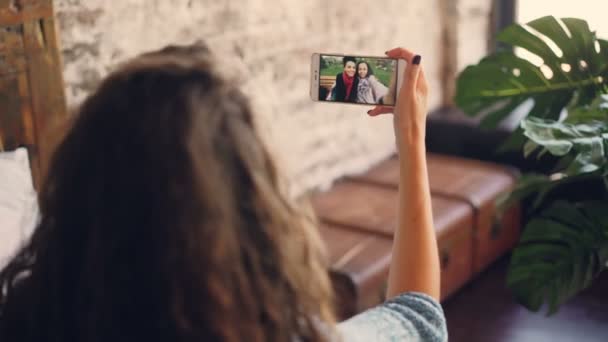 Donna dai capelli scuri che parla con le amiche online con lo smartphone, la ragazza sta guardando lo schermo, tenendo il dispositivo e parlando. Concentrati sullo schermo dello smartphone . — Video Stock