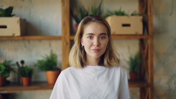 Slow motion portrait of happy young lady looking at camera and smiling then laughing standing in nice modern apartment wearing casual clothing. People and emotions concept. — Stock Video