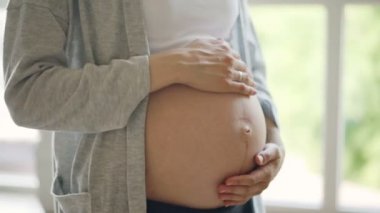 Bekliyor anne kapalı arka planda büyük pencere ile ayakta onu koca bebek carpma okşayarak. Mutlu hamilelik, insanlar, sevgi ve hassasiyet kavramı.