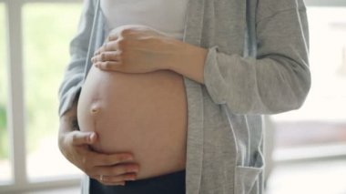 Karın ve ihale anneler Close-up sevecen ve okşayarak bebek carpma sevgi ve bakım eller. Mutlu hamilelik, annelik ve doğurganlık kavramı.