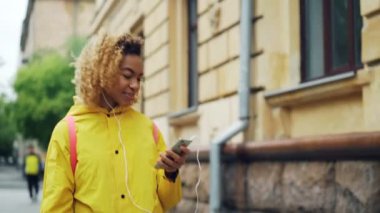Yakışıklı Afro-Amerikan Bayan kulaklık giyen radyo dinleme ve modern smartphone holding, kız şarkı ve müzik ve ritim tadını.