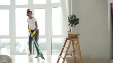 Afro-Amerikan Kız güzel derli toplu düz, Genç kadın ev işi yapıyor silmekten ve having fun müzik, dans ve şarkı. Temizlik ve ev kavramı.