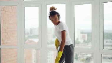 Yaratıcı karışık ırk kadın kulaklık müzik, dans ve şarkı temizlik sırasında evde, rutin iş zevk yıkama zemin ve sahip eğlenceli bir kızdır.