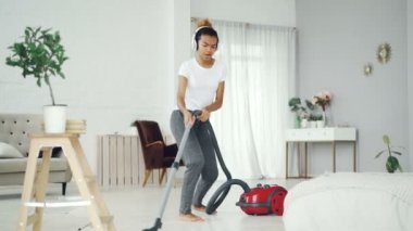 Yaratıcı Afrikalı-Amerikalı genç güzel daire, yerde kulaklık ile müzik, dans ve şarkı yapmak. Elektrikli ev aletleri ve eğlence kavramı.