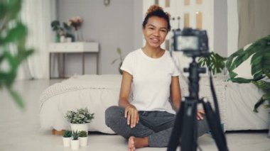 Kadın blogger video kamera, gülümseyen ve duygusal evde yatak odası katta oturan konuşurken bakarak videolog için kaydediyor. İnsanlar ve sosyal medya kavramı.