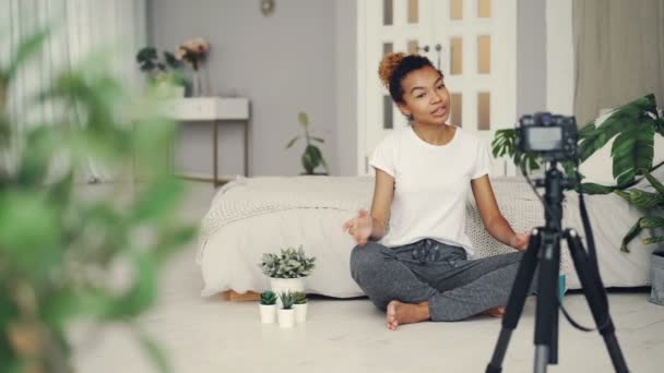 Blogueiro criativo alegre jovem está gravando vídeo para seu blog de internet falando, sorrindo e olhando para a câmera no tripé. Conceito de tecnologia e mídia de massa . — Vídeo de Stock