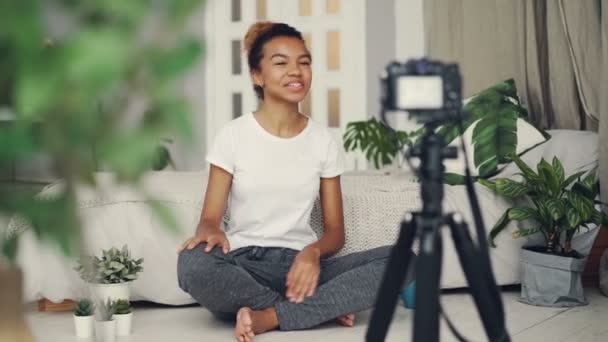 Feliz mujer afroamericana vlogger está grabando vídeo para el blog en línea, ella está mirando a la cámara, contando con sus dedos y hablando con sonrisa alegre . — Vídeo de stock