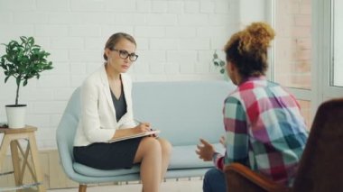 Kendine güvenen kadın psikolog onu dinlerken ve hasta açıklayan sorun konuşuyor iken yazma Afrikalı-Amerikalı kız ile istişare tutuyor.