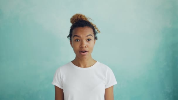 Ritratto di donna afroamericana sorpresa che guarda la macchina fotografica che solleva le sopracciglia e apre bocca esprimendo stupore. Concetto di persone, emozioni e reazioni . — Video Stock