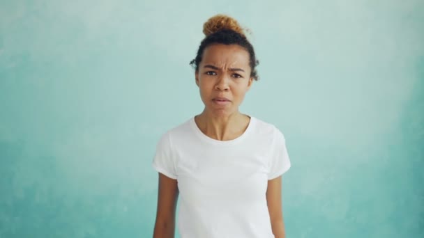 Portrait de femme métisse en colère parlant et gestualisant exprimant des émotions négatives debout sur fond bleu clair. Sentiments et concept de personnes . — Video