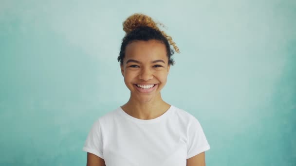 Gros plan portrait au ralenti d'une jeune femme joyeuse aux cheveux bouclés regardant la caméra et souriant exprimant des sentiments et des émotions positives. Les gens et le concept amusant . — Video