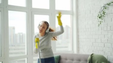 Mutlu genç sarışın ev işi yapıyor ve modern evde eğlenmek, o yerde paspas ile şarkı ve dans aracılığıyla dinlerken yıkıyor.