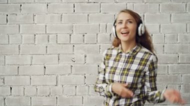 Şarkı ve dans tuğla duvar arka planı kulaklık üzerinden müzik çekici kız portresi. Gençlik Kültür, millennials ve yaşam tarzı kavramı.