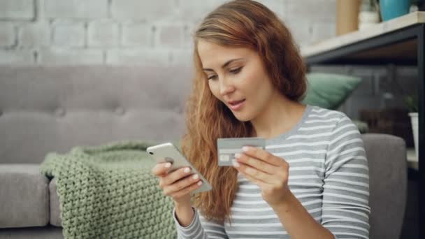 Die aufgeregte junge Frau macht Online-Zahlungen mit Bankkarte und berührt den Smartphone-Bildschirm und lächelt dann glücklich. Finanzen, Internet-Shopping und Jugendkonzept. — Stockvideo