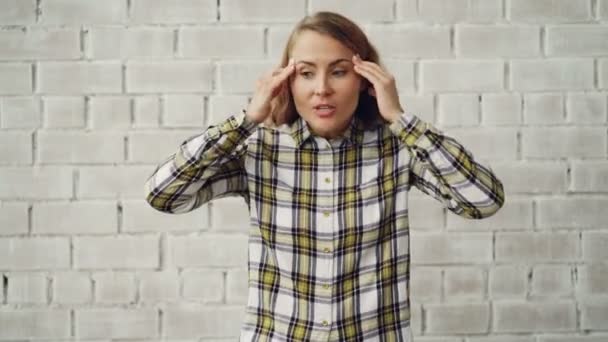 Portrait d'une jeune femme en colère criant et gesticulant exprimant des émotions négatives debout sur un fond de mur de briques. Sentiments humains et concept humain . — Video