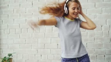 Heyecanlı genç bayan yatağa dans ve kulaklıklar giyen ve yalnız evde müzik şarkı var. Modern teknoloji, daire ve şarkı kavramı.