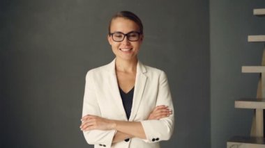 Ağır çekim portre resmi giyim ve gözlük kameraya bakarak ve gülümseyen genç iş kadını. Kendine güvenen insanlar, gençlik ve pozitif kavramı.
