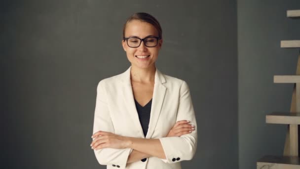 Retrato em câmera lenta de uma jovem empresária vestindo roupas formais e óculos olhando para a câmera e sorrindo. Pessoas confiantes, juventude e conceito de positividade . — Vídeo de Stock